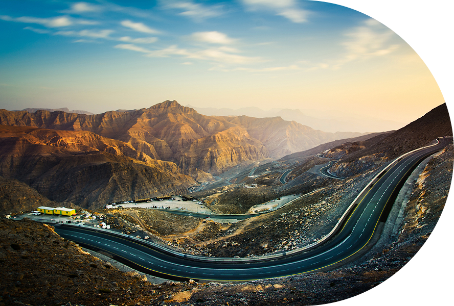 Winding mountain road under a cloudy sky.